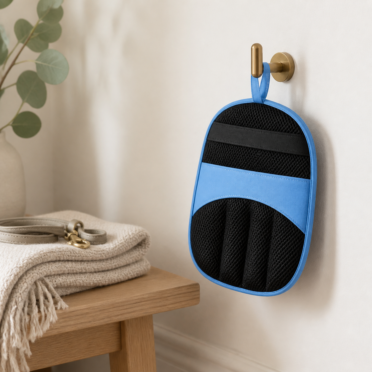 Blue Avenlo pet hair removal mitt hanging beside a tidy entryway bench